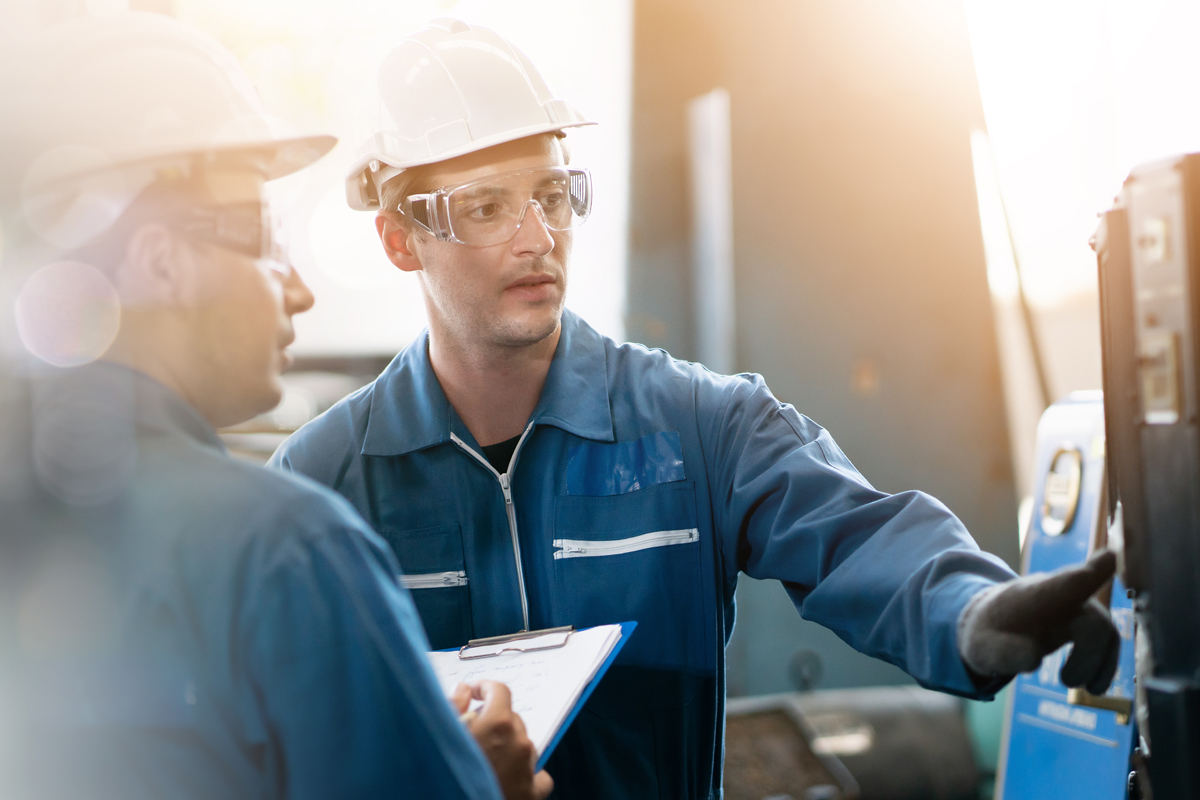 Picture of two workers attending to a machine.