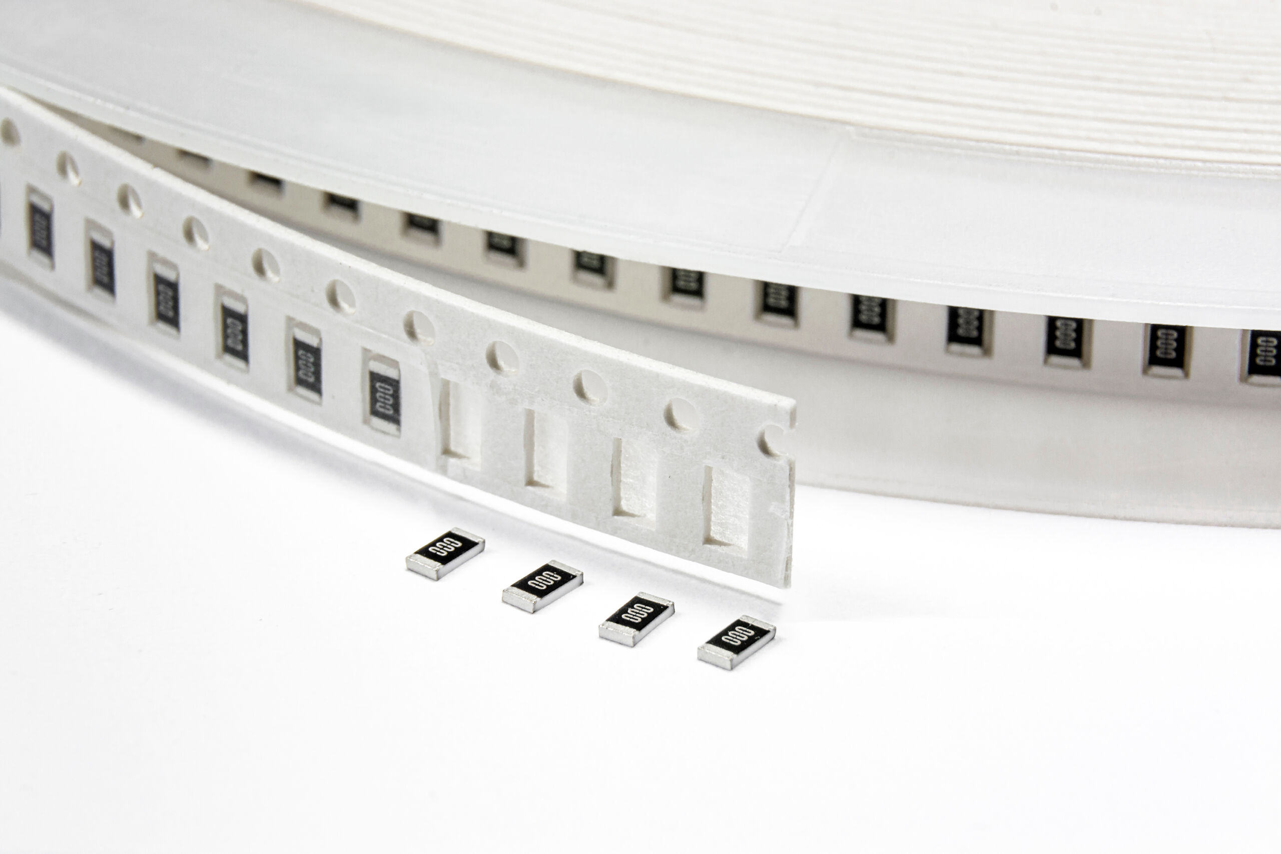 smd_detail_pieces_showcase Image of an SMD taping spool showcasing four (4) capacitors